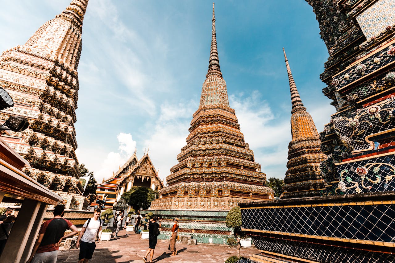Stunning view of traditional pagodas at Wat Pho under a vibrant blue sky in Bangkok, Thailand.
