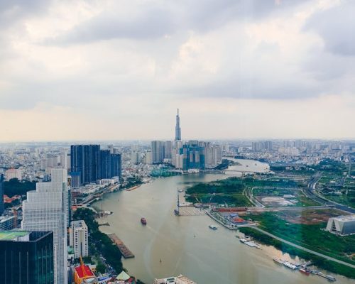 Captivating aerial image showcasing Saigon's vibrant skyline and river with modern skyscrapers and cloudy sky.